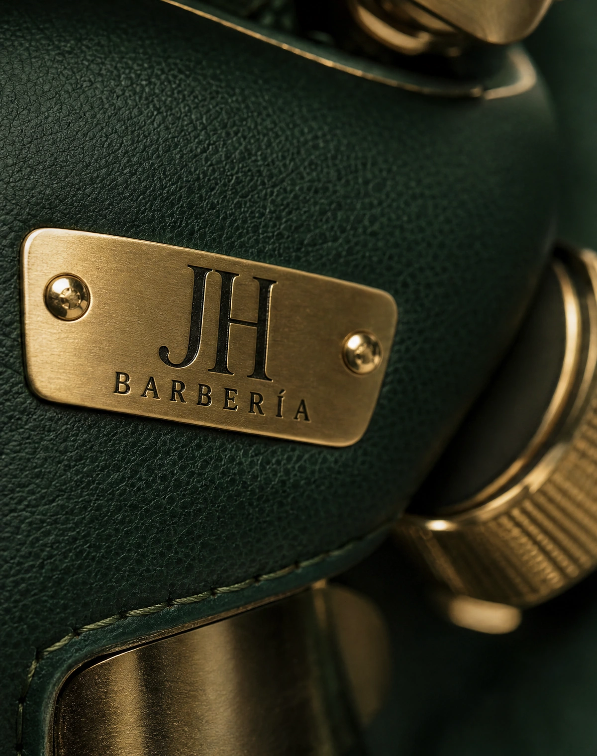 Detalle de cuero verde con placa dorada JH Barbería